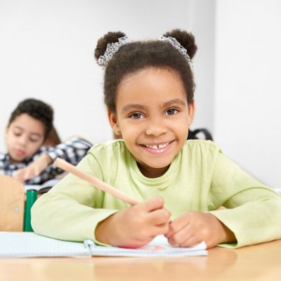 schoolgirl-smiling-posing-in-classroom-at-primary-school-p4la9qdytq66dmr2yz9mxgo8cz8zq9bqufguuacwww